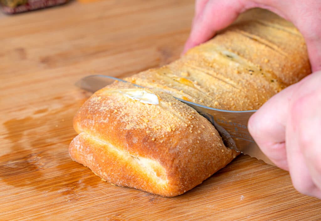 slicing pepperoni bread with a bread knife