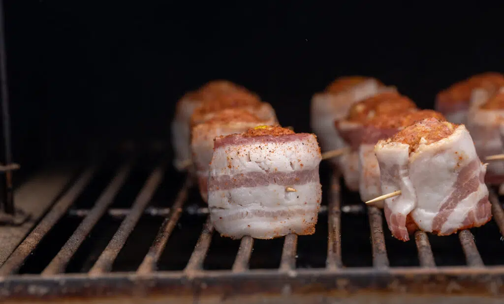 raw bacon wrapped meatballs on the grill