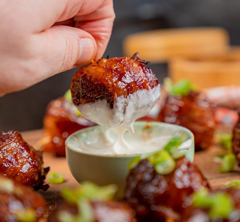 Dipping bbq bacon wrapped pork meatball in ranch