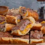 sliced brat bread on a wooden board with melted cheddar
