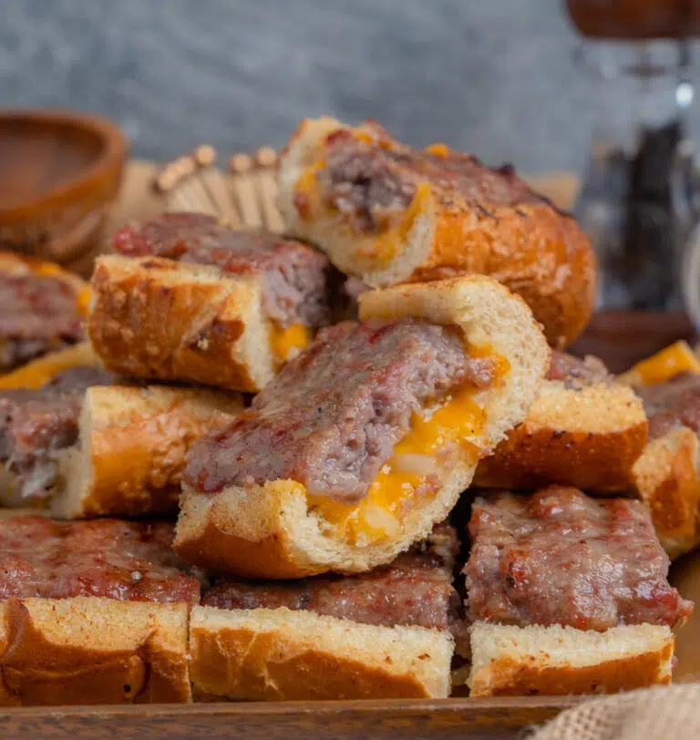 sliced brat bread on a wooden board with melted cheddar