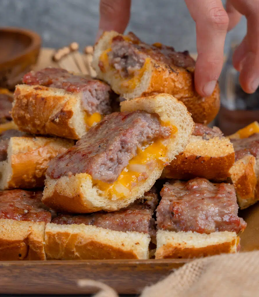 a pile of brat bread with a hand grabbing a slice