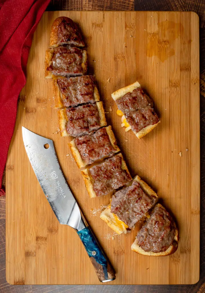 sliced loaf of brat bread with large dal strong knife on cutting board