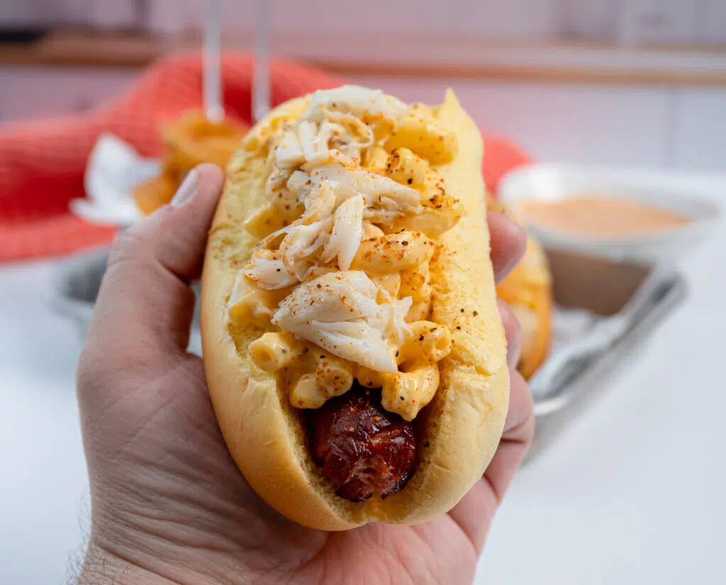 picking up a crab Mac and cheese hot dog