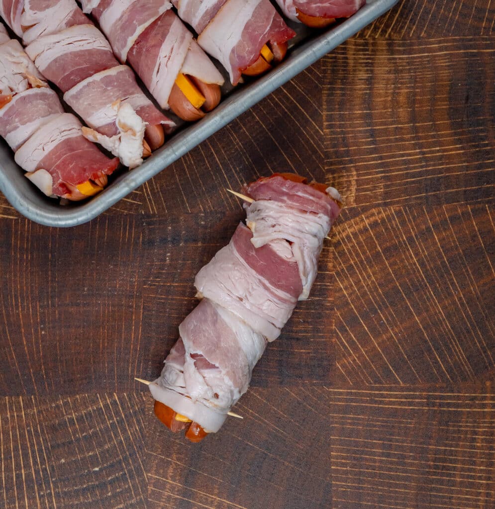 raw bacon wrapped hot dog with cheddar cheese