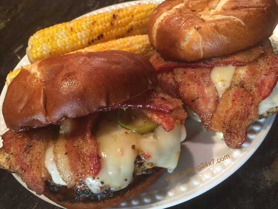 Grilled chicken breast sandwich with bacon, cheese and jalapeno peppers on a pretzel roll