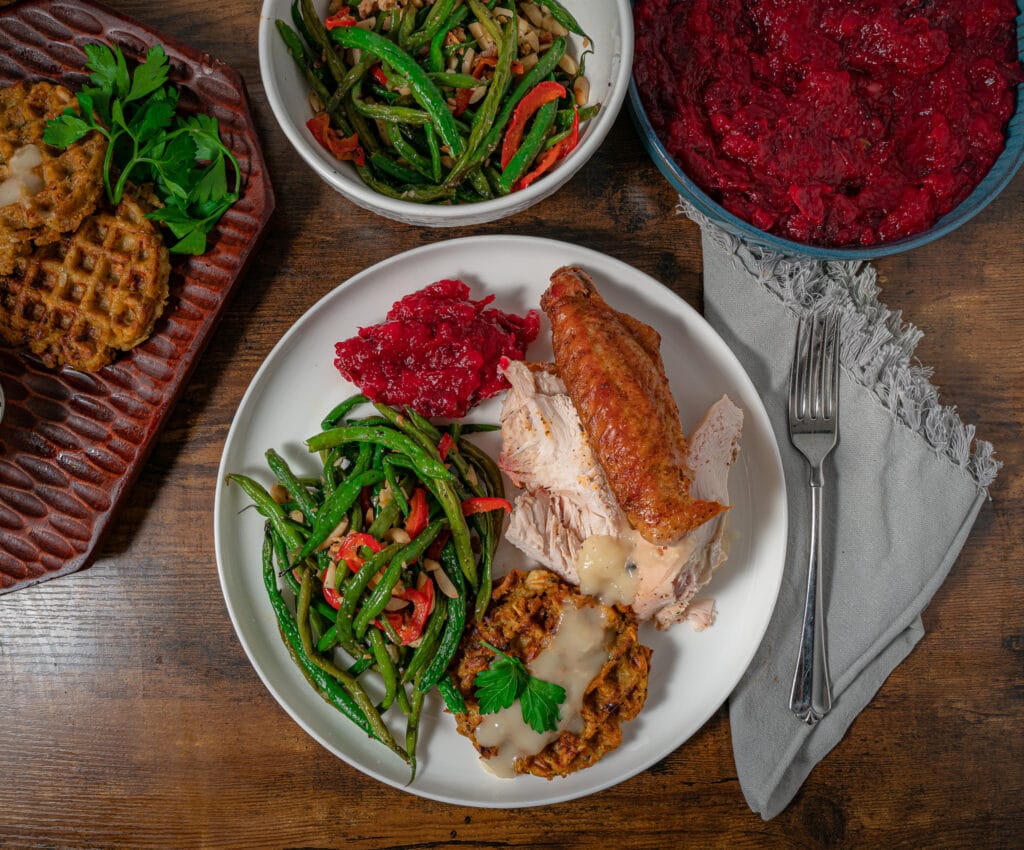 holiday dinner plate with green beans cranberry sauce and smoked turkey