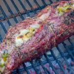 stuffed flank steak rolled up on a grill