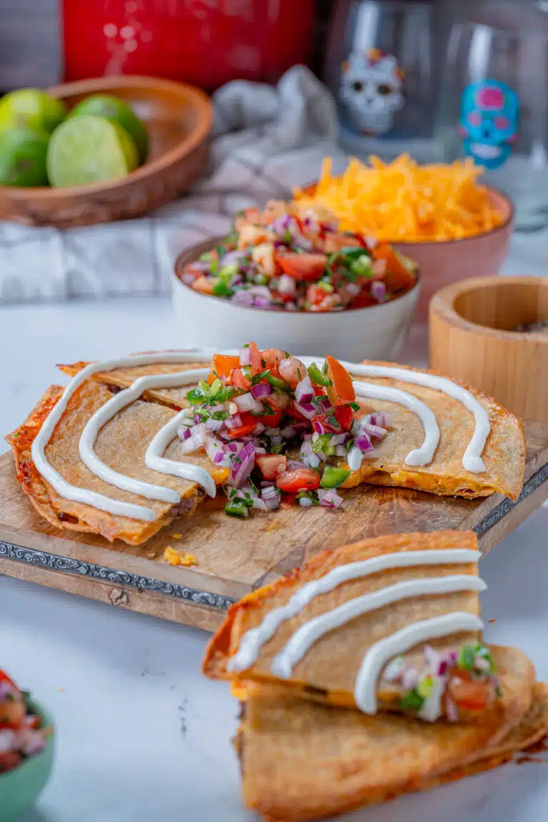 steak quesadilla topped with sour cream on a cutting board