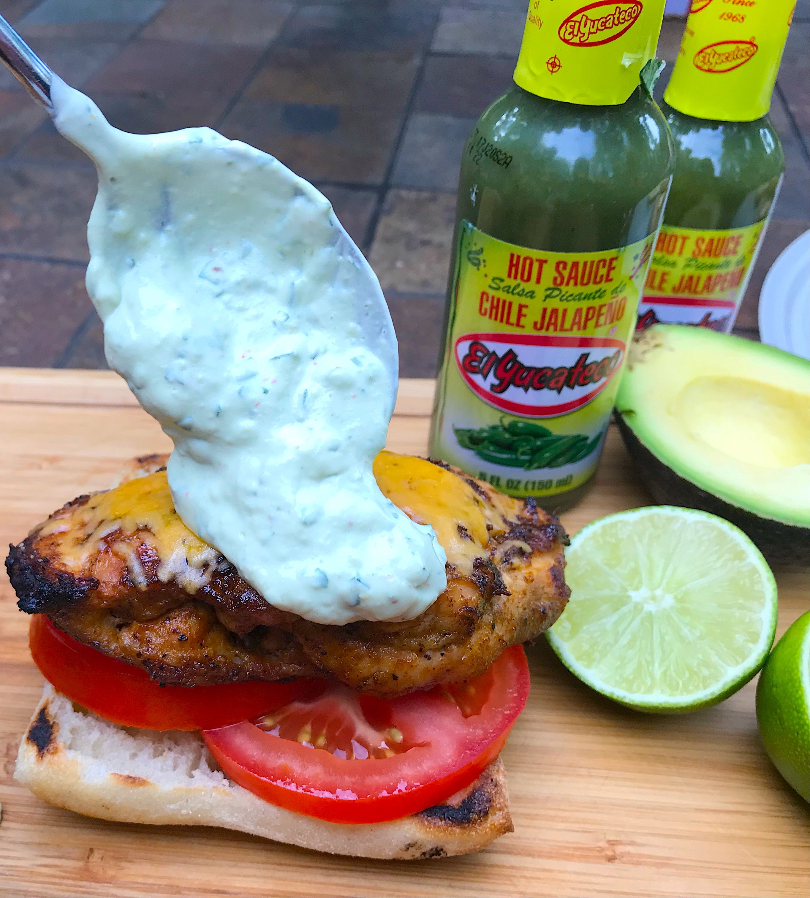 putting Avocado Jalapeño Crema on grilled chicken with spoon