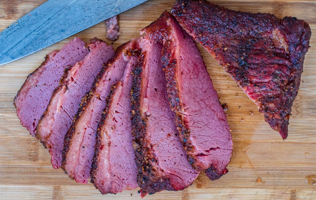 Smoked corned beef sliced on wooden cutting board