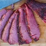 Smoked corned beef sliced on wooden cutting board