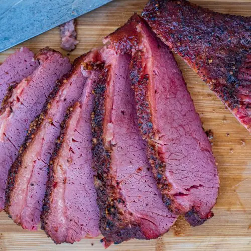 Smoked corned beef sliced on wooden cutting board