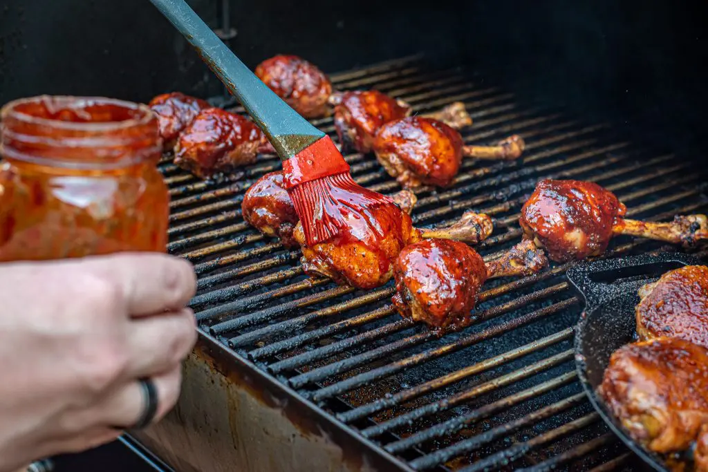 brushing barbecue sauce on chicken drumstick lollipops