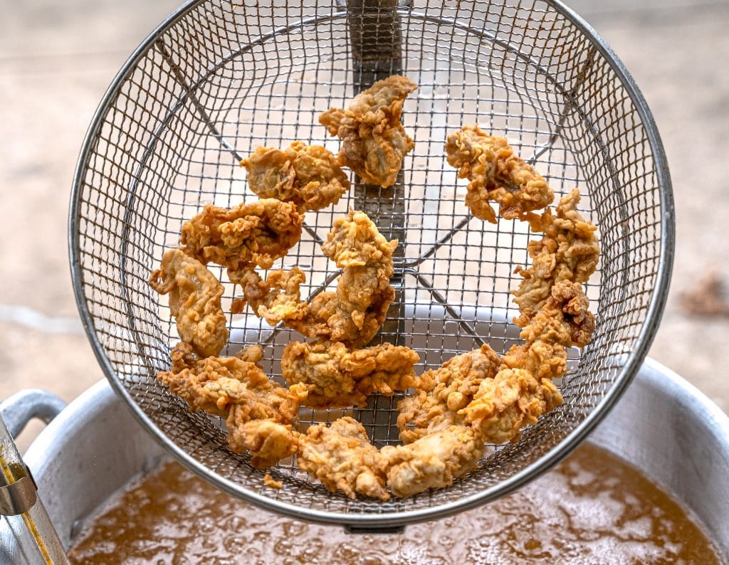 deep fried oysters in a basket just out of the hot frying oil