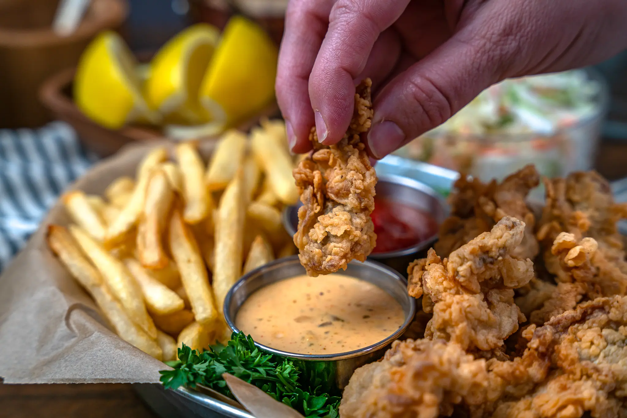 dipping a crispy fried oyster in remoulade dipping sauce