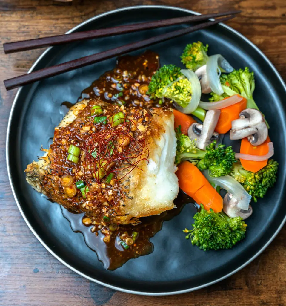 Pan seared Chilean Sea Bass topped with spicy hoisin vinaigrette with seamed veggies