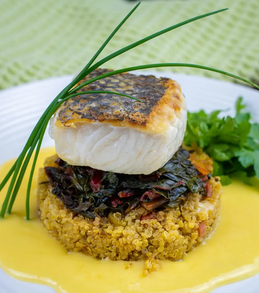 Pan seared Chilean Sea Bass with crispy skin on top of quinoa with yellow sauce 