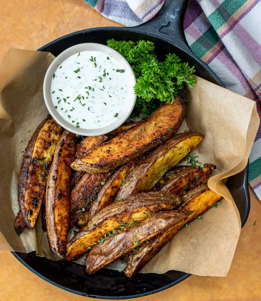 cast iron skillet filled with potato wedges and creamy horseradish aioli