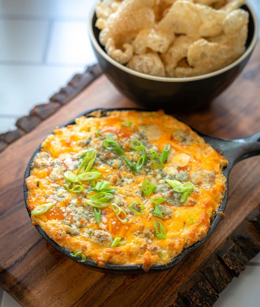 keto buffalo chicken dip served in a cast iron skillet with pork rinds
