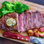 New York strip steak sliced and served with broccoli and garlic compound butter