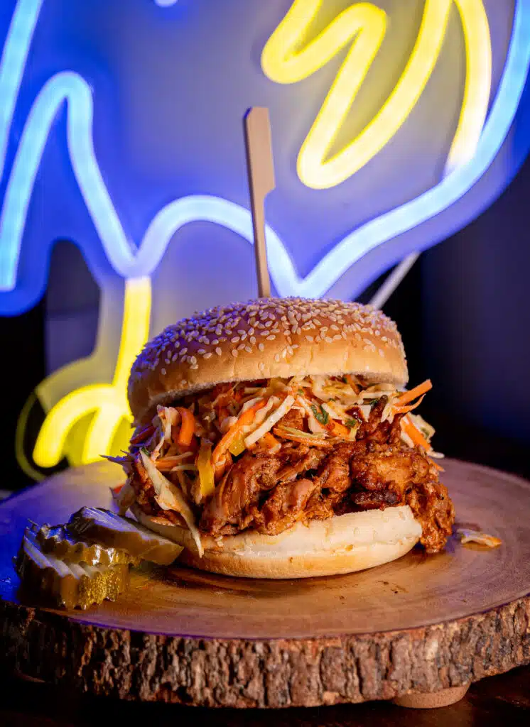 Carolina Smoked Pulled chicken sandwich with a neon light in the background