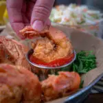 fried shrimp dunked into cocktail sauce