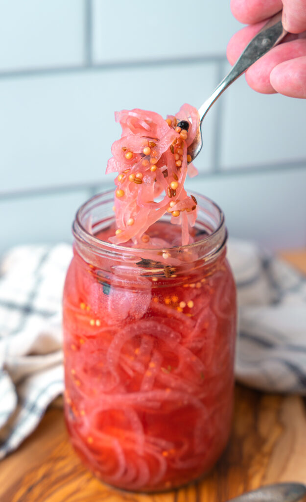 using a fork to scoop pickled red onions out of mason jar