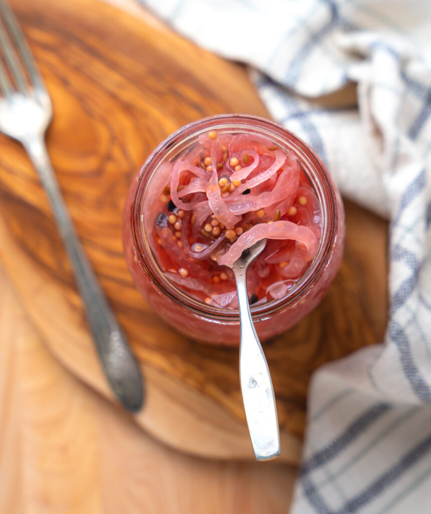 a fork sitting in a mason jar of pickled onions