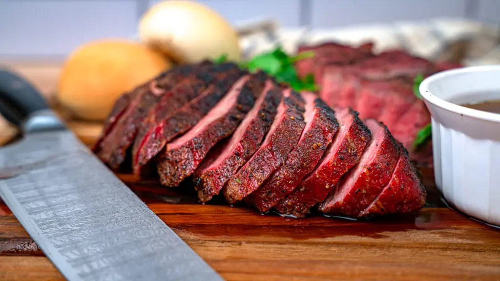 sliced smoked Tri Tip on a cutting board with smoked au jus