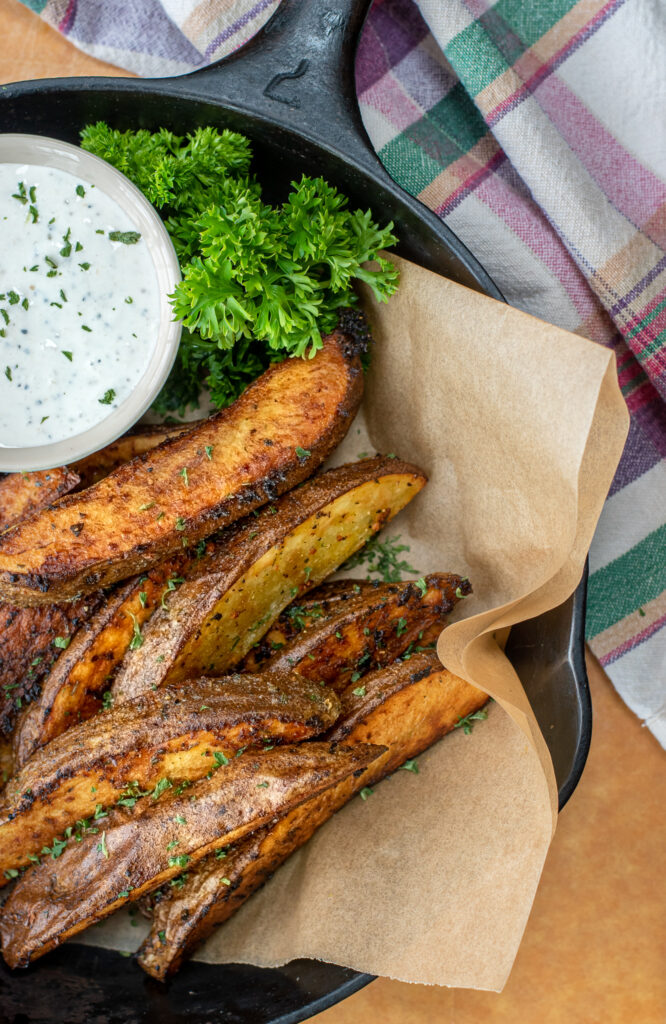 potato wedges in a skillet with spicy horseradish dipping sauce