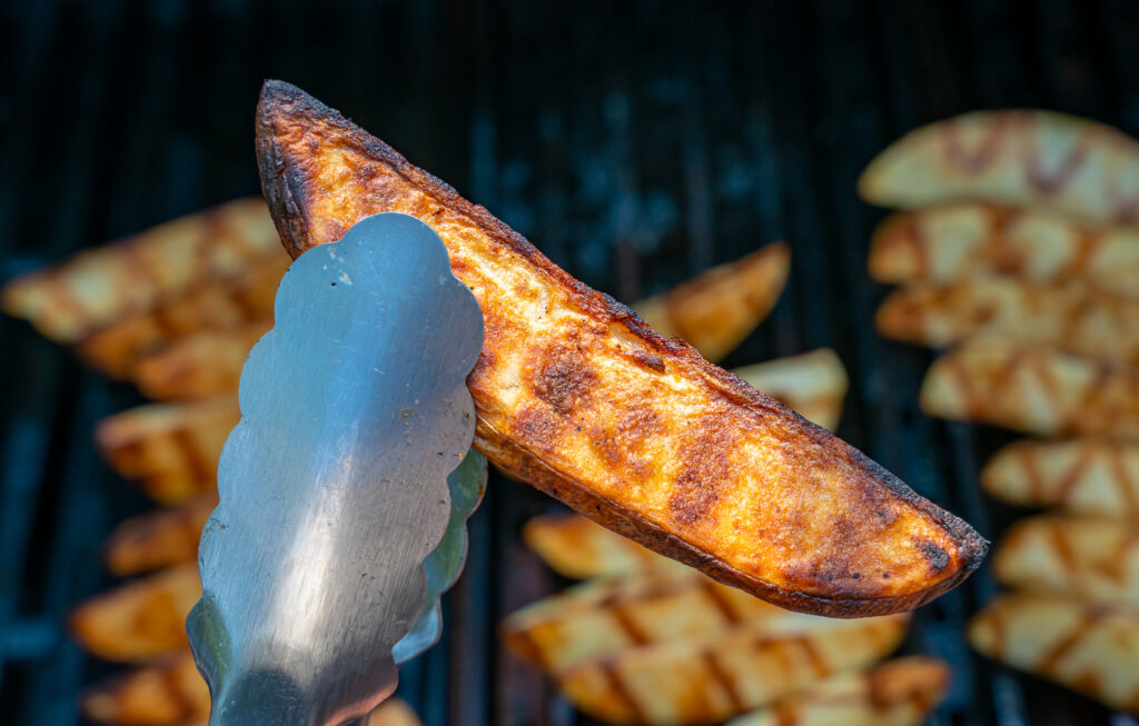 grilled potato wedge grabbed with tongs