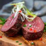 sliced beef tenderloin garnished with diced peppers chives and scallions