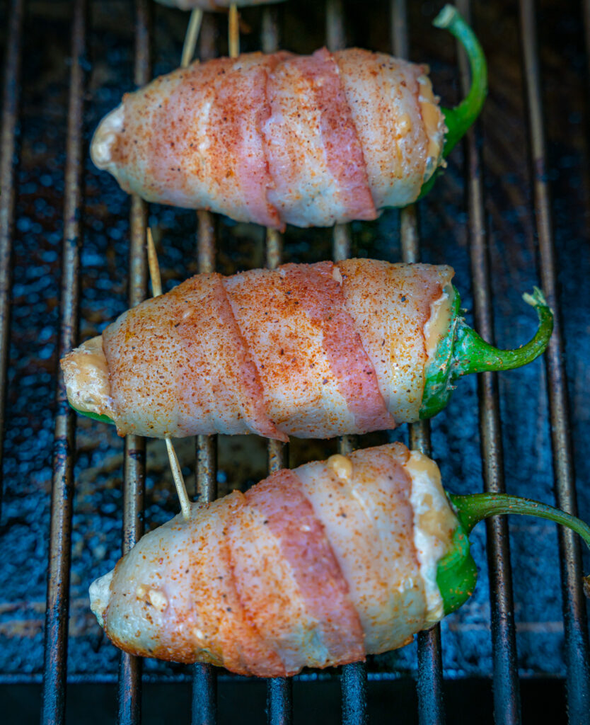 uncooked bacon wrapped jalapeños on the smoker