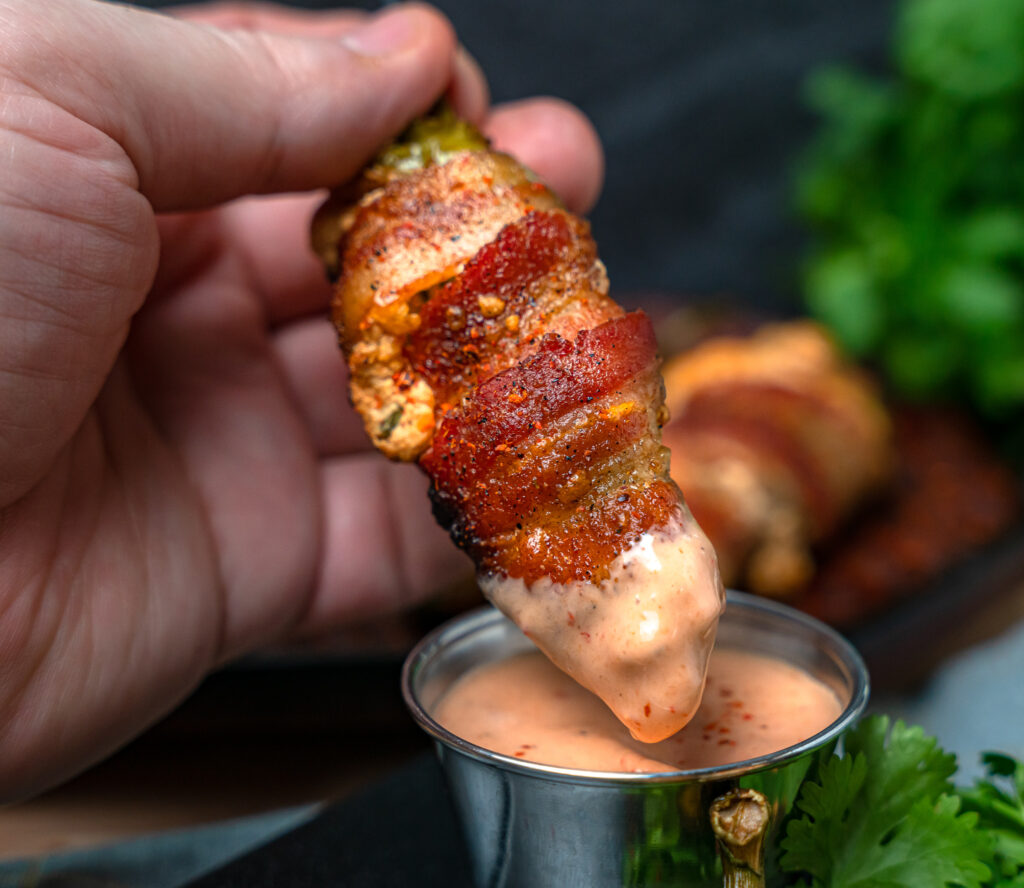 dipping crispy bacon wrapped japalpen pepper in spicy ranch