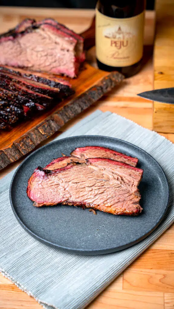 sliced brisket on a plate with wine in the background