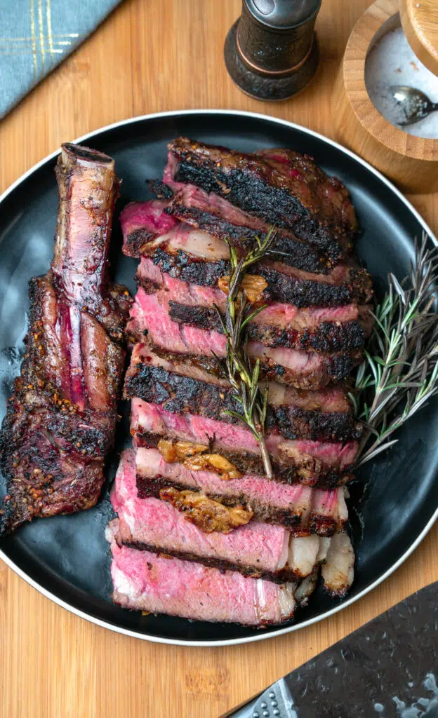 brown in cowboy ribeye sliced and served on a black plate