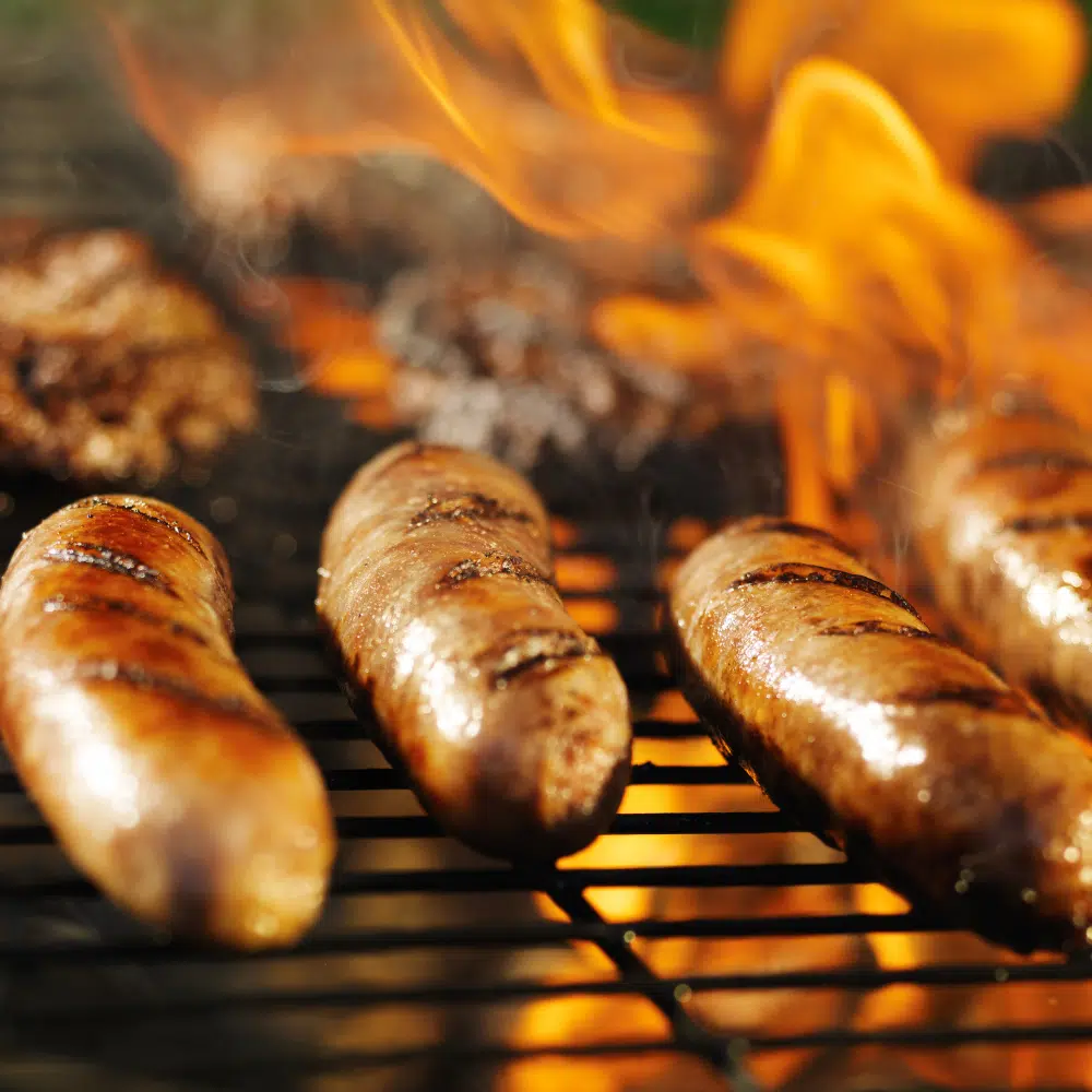 brats on a grill with flames