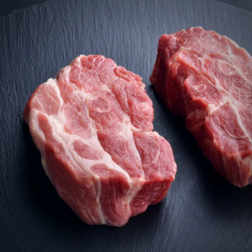 raw pork shoulder cut in half on a slate block