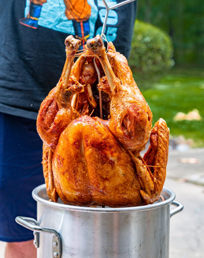 pulling a deep fried turkey out of a pot of oil