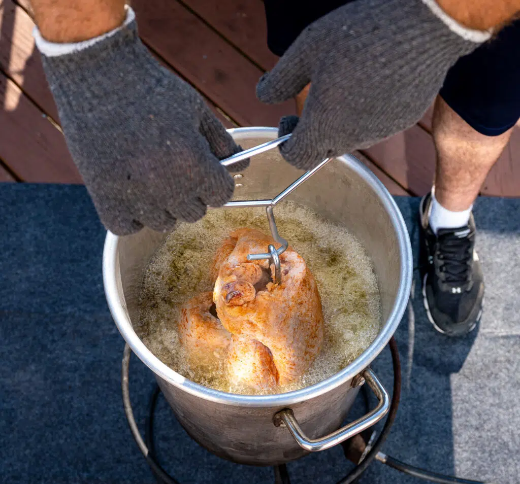 turkey being lowered into large pot of peanut oil