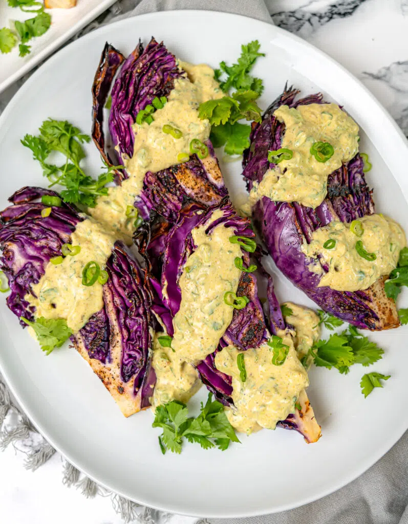 grilled red cabbage wedges with curry yogurt sauce on a platter
