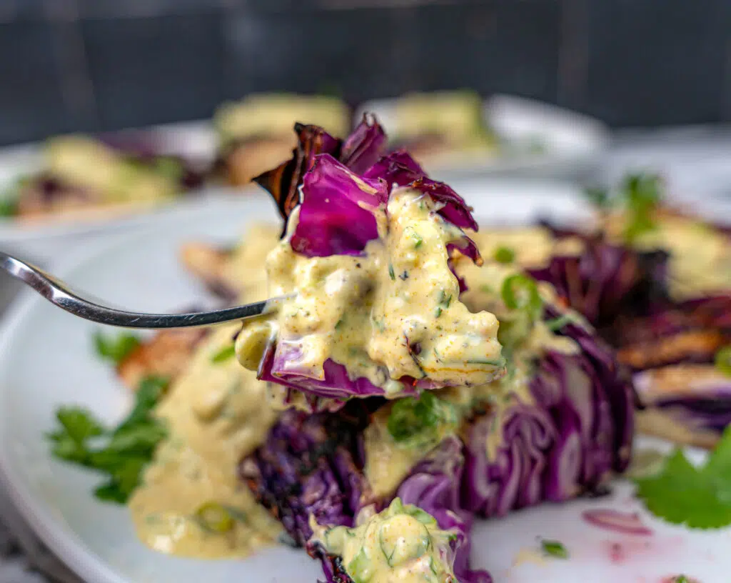 a bite of grilled red cabbage with yogurt sauce