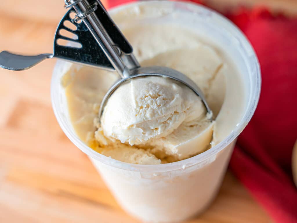 scooping pawpaw ice cream out of a quart container