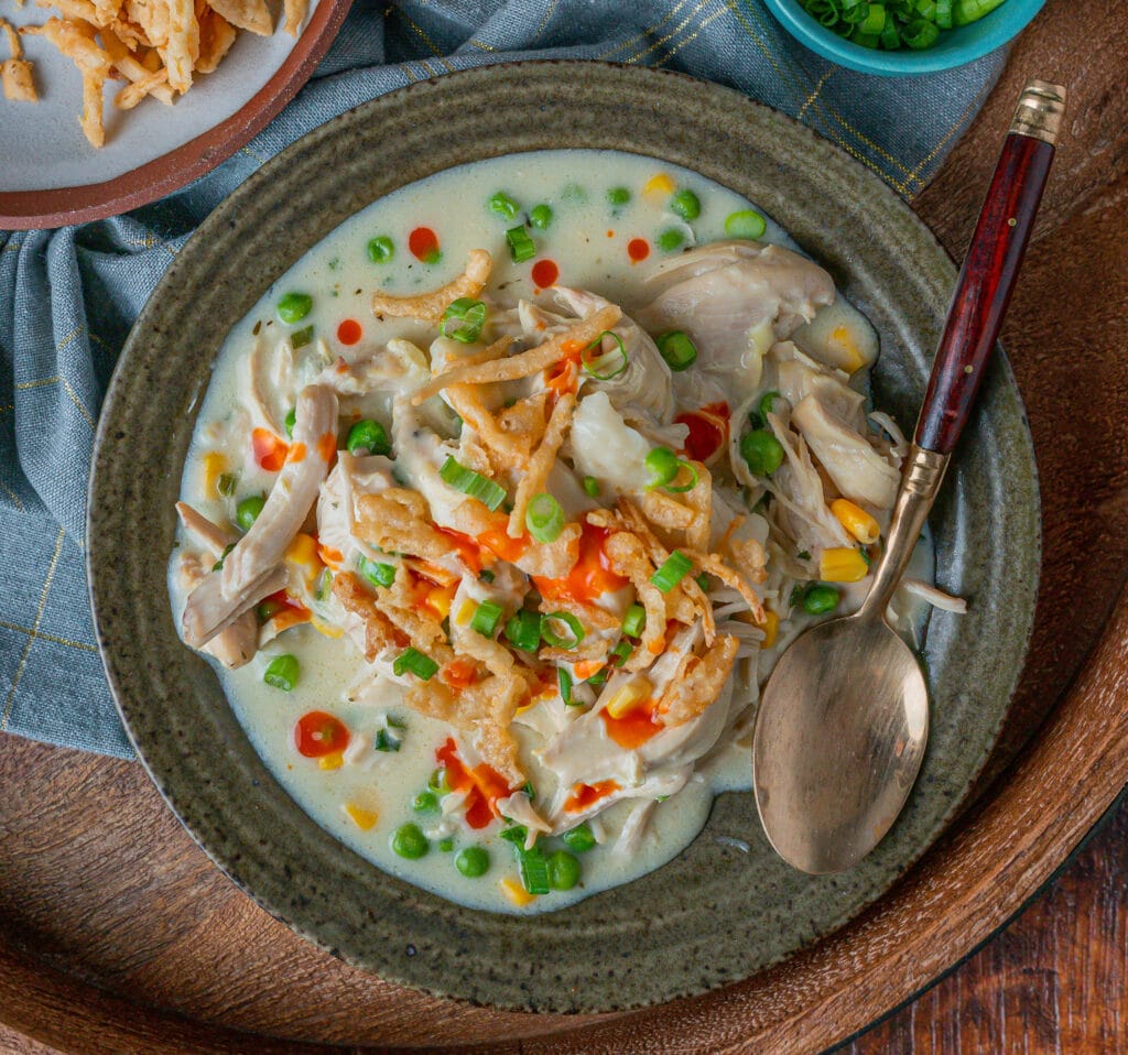 Easy chicken and dumplings recipe topped with crispy onions and hot sauce