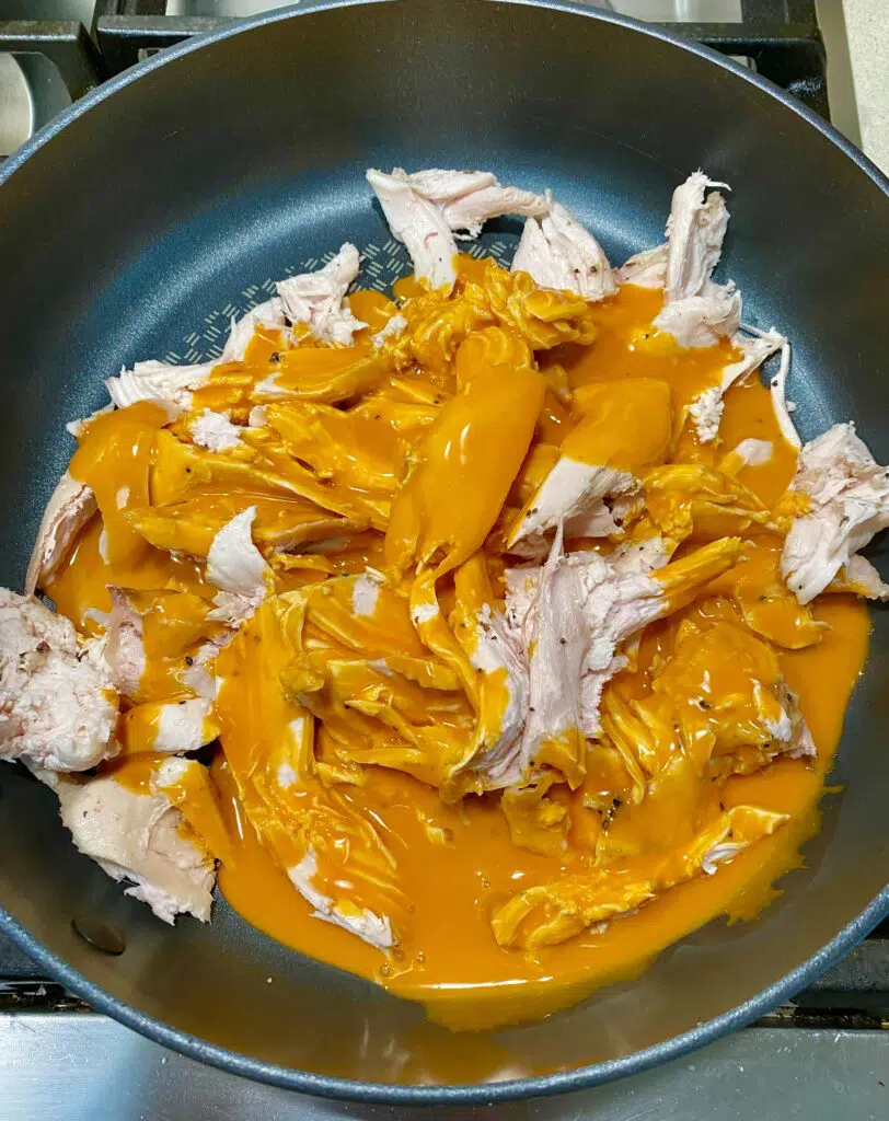 cooking shredded buffalo chicken in a pan