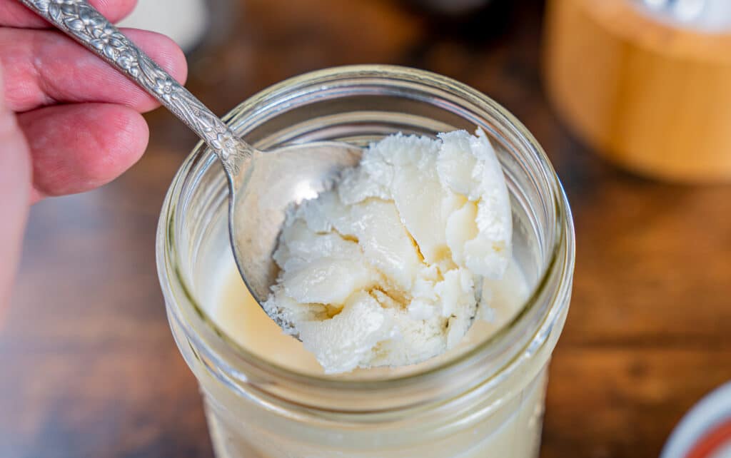 scooping homemade beef tallow out of the jar