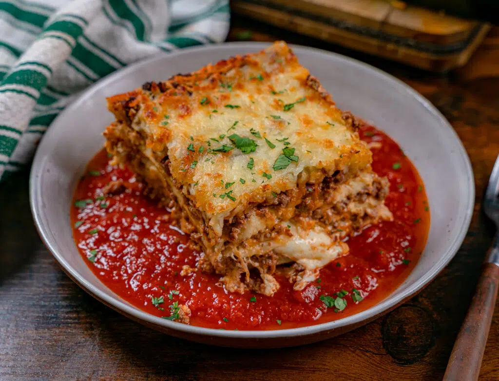 Ground venison lasagna over a bed of tomato sauce