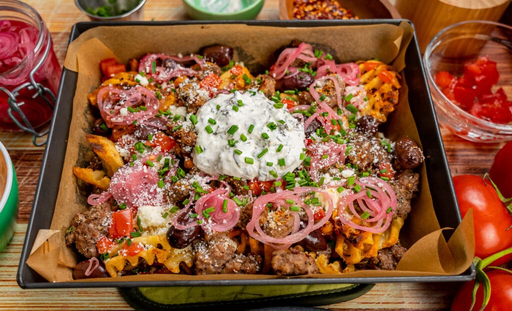 pan of loaded fries topped with lamb, feta, tomatoes olives and more