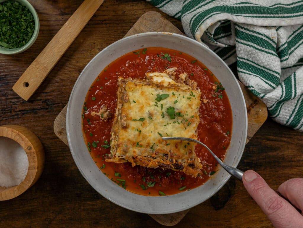 cutting into venison lasagna with tomato sauce